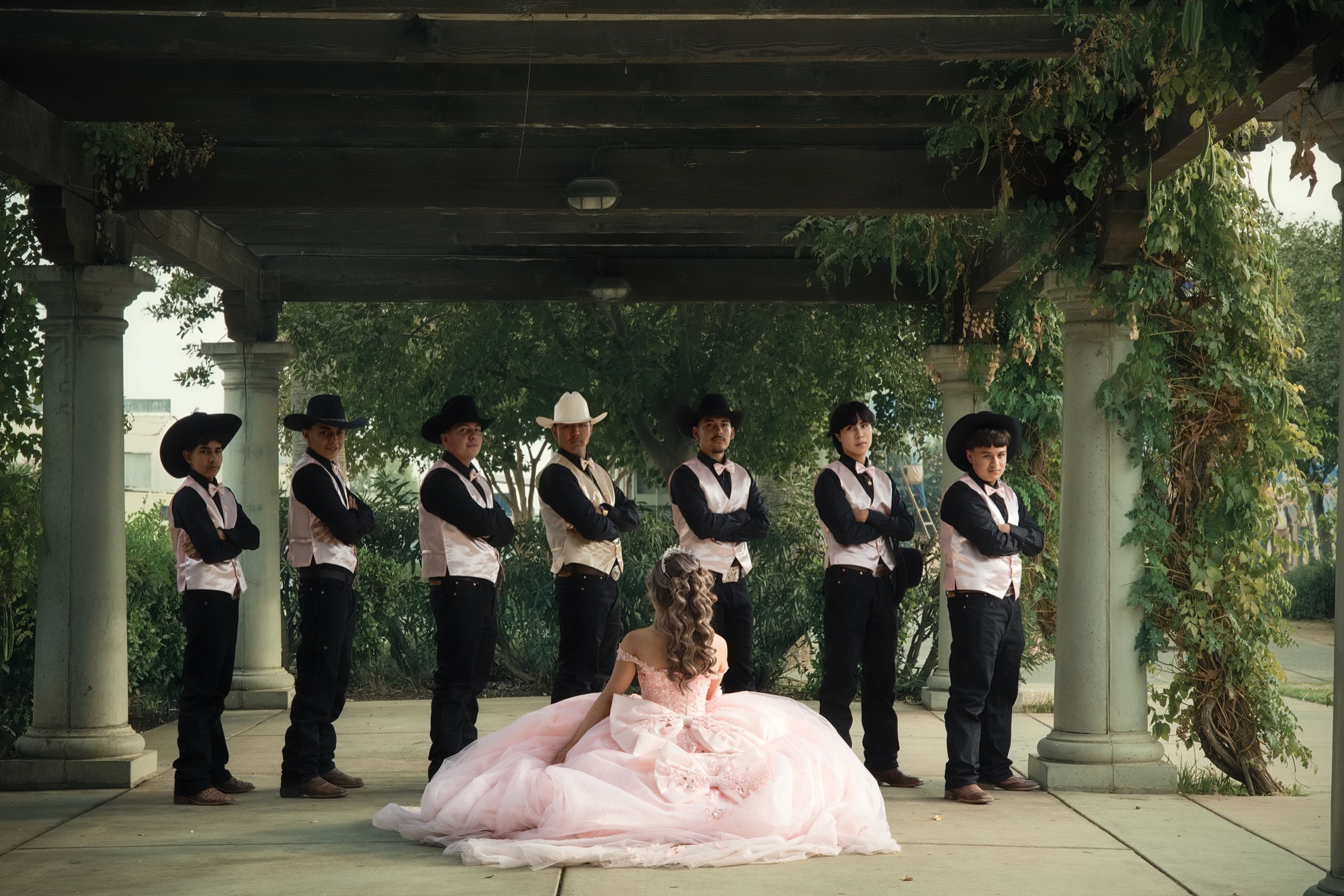 Quinceañera with chambelanes under a garden pergola