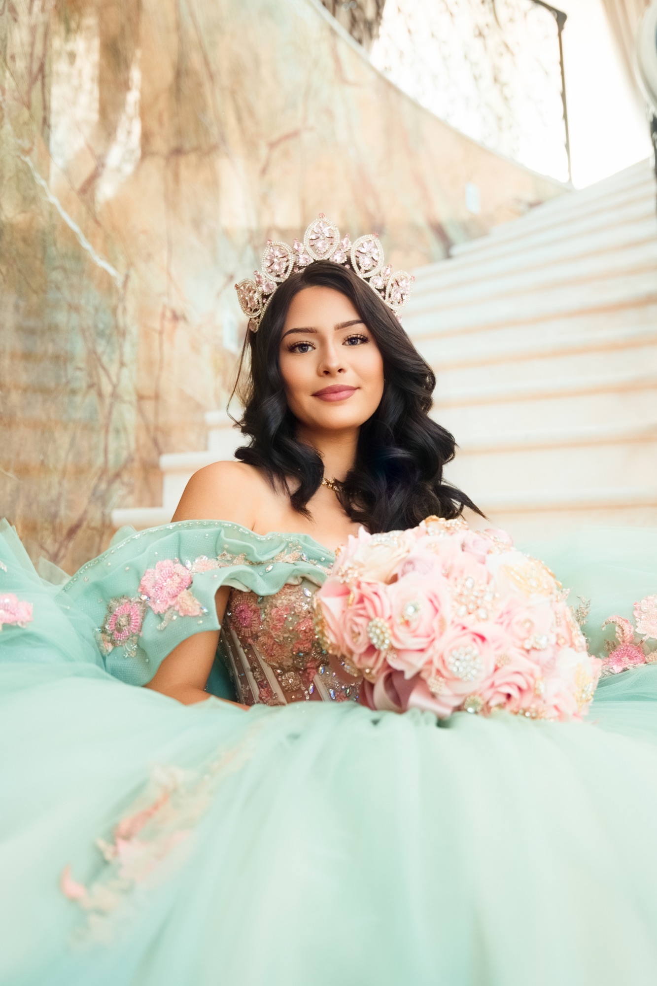 Quinceañera portrait in a mint dress on a marble staircase