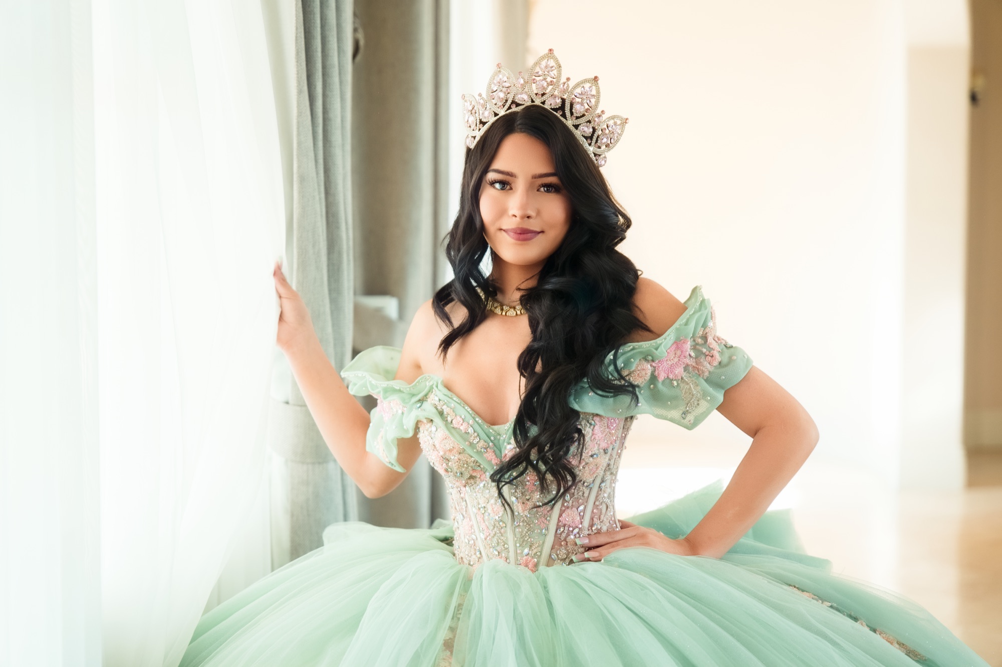 Quinceañera portrait by a bright window in a mint dress